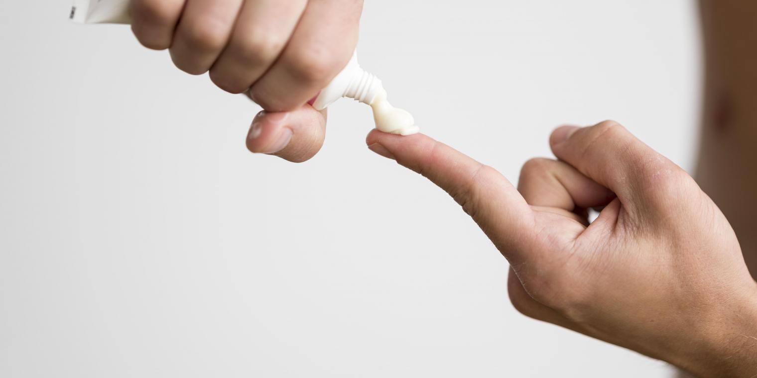 man-squeezing-cream-from-tube-his-finger